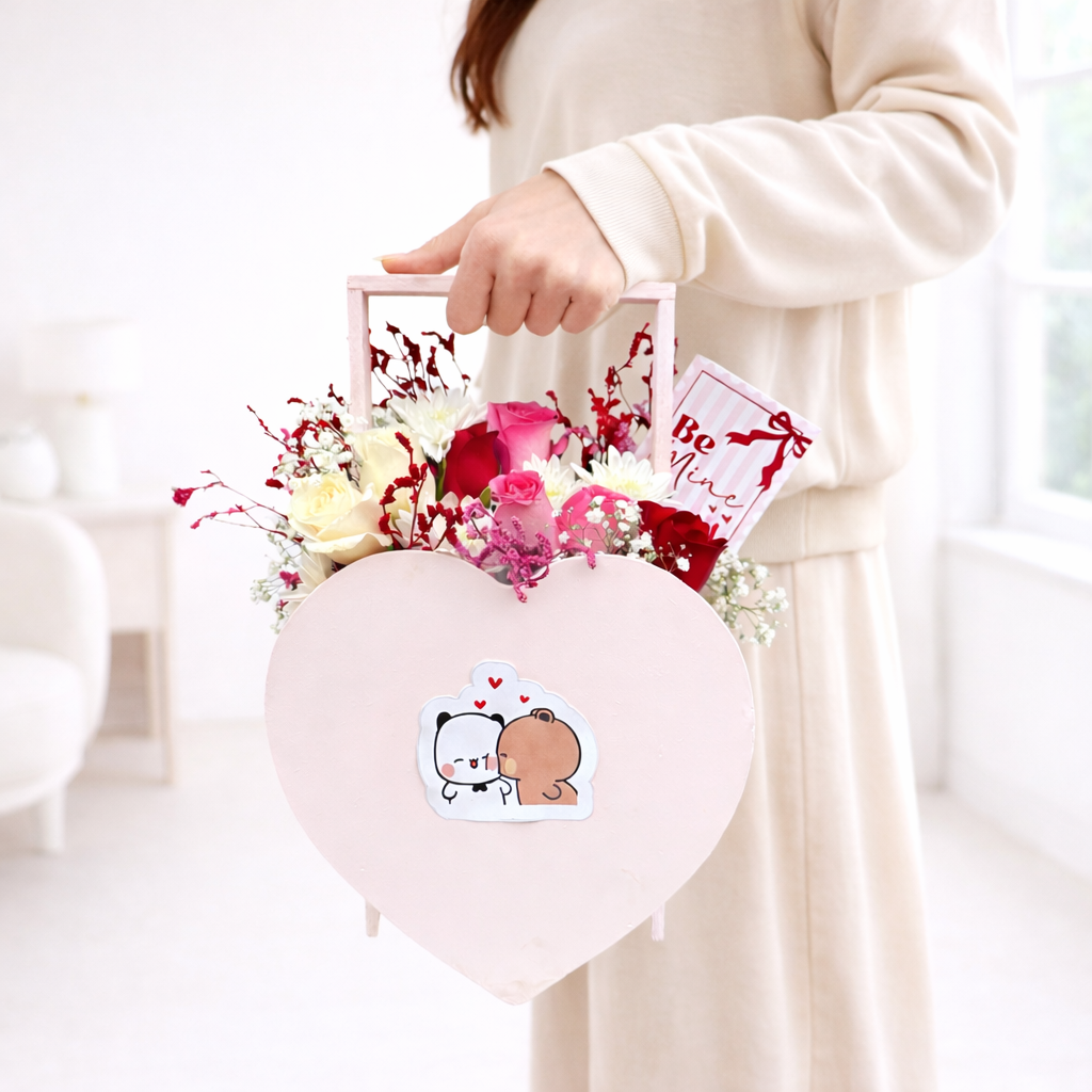 Heart-shaped box with flowers and a card held by a person against a white background