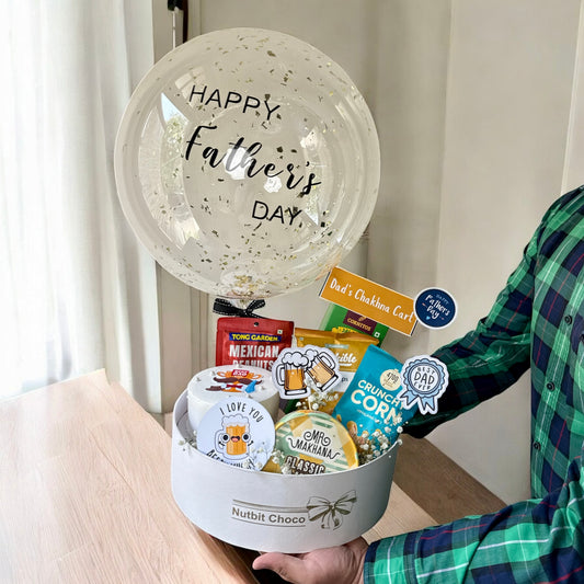 Gift basket with snacks and a balloon labeled 'Happy Father's Day' held by a person.