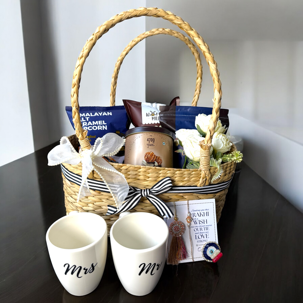 Gift basket with 'Mr' and 'Mrs' mugs on a dark surface