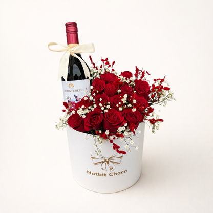 Bottle of wine and bouquet of red roses in a white container on a white background