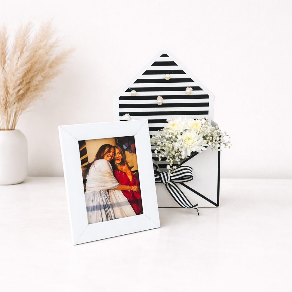 Decorative photo frame with a striped design on a white surface with a vase and flowers.
