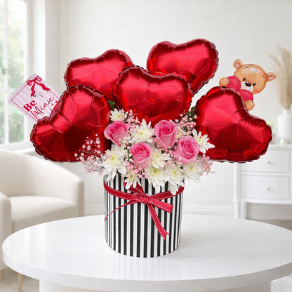 Bouquet of flowers with heart-shaped balloons and a teddy bear in the background