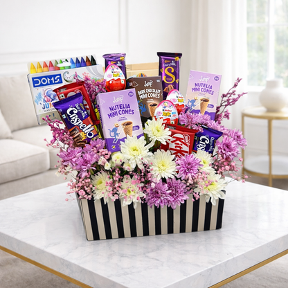 Gift basket with flowers and snacks on a coffee table in a living room.