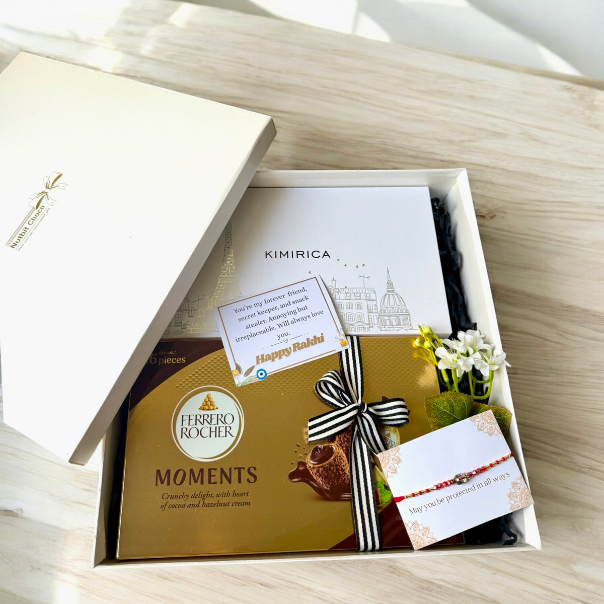 Gift box with Ferrero Rocher Moments, Kimirica card, and decorative elements on a wooden surface.