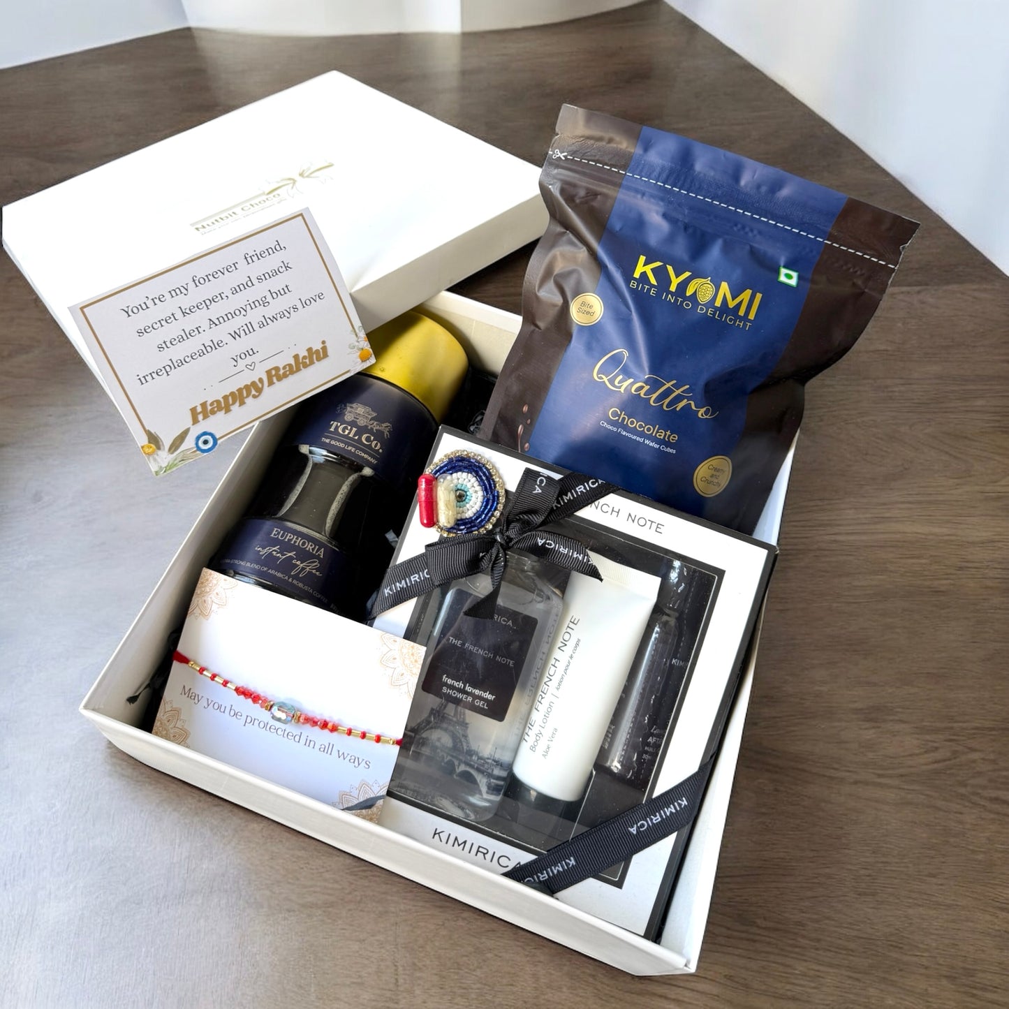 Gift box with various items including a bottle, cream, and chocolate on a wooden surface.