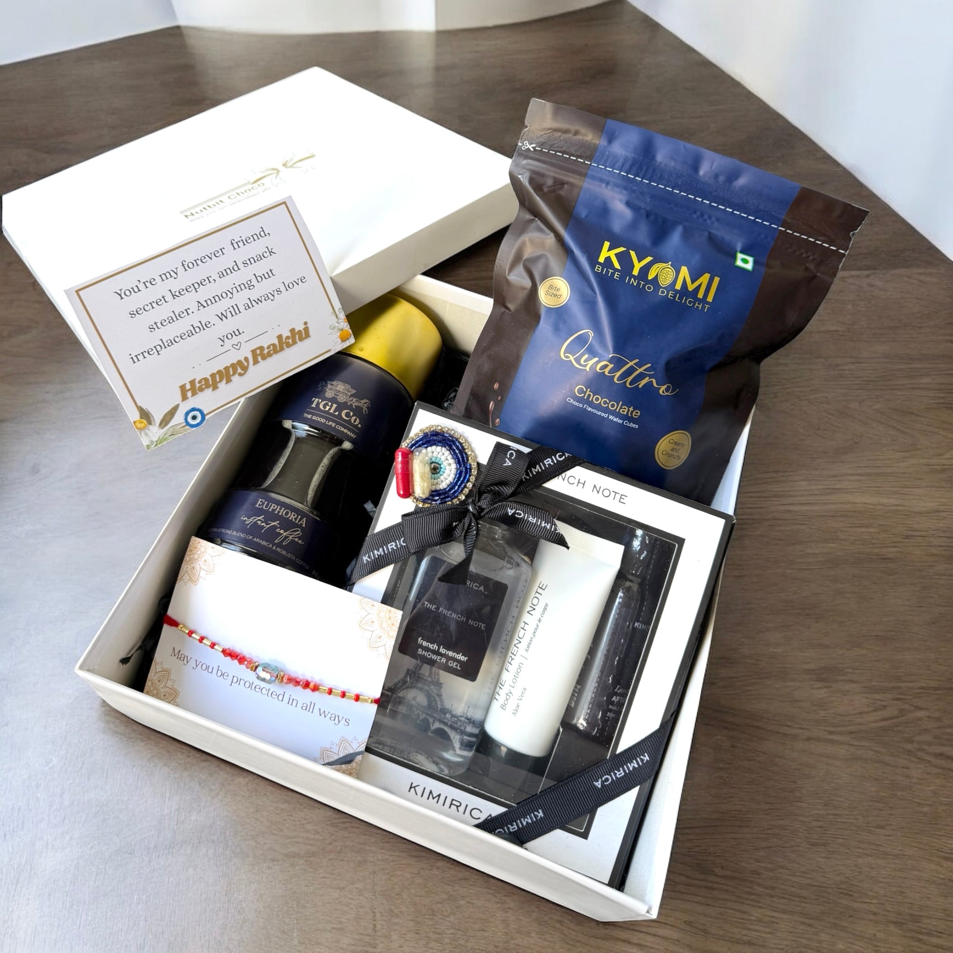 Gift box with various items including a bottle, cream, and chocolate on a wooden surface.