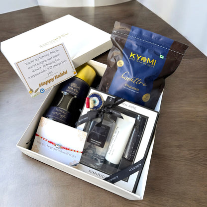 Gift box with various items including a bottle, cream, and chocolate on a wooden surface.