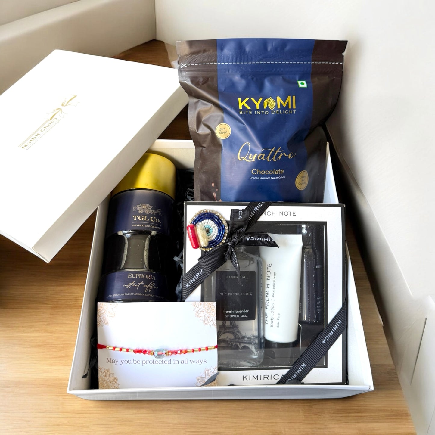 Gift set with coffee, chocolate, and skincare products in a box on a wooden surface.
