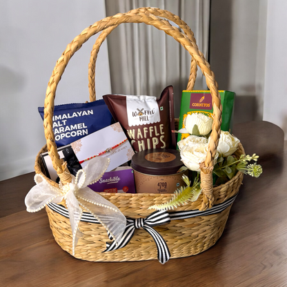 Woven gift basket with snacks and a candle on a wooden surface