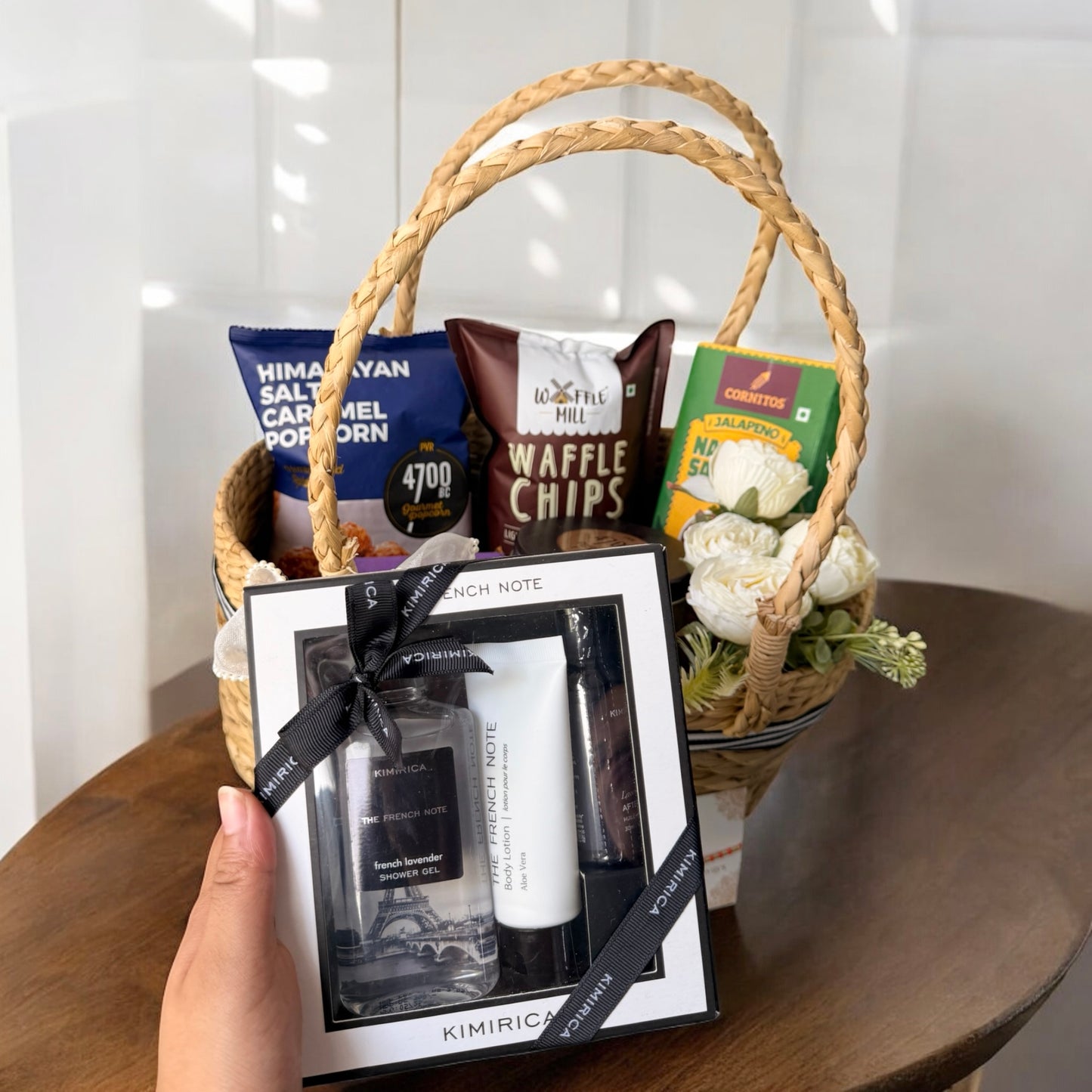Gift basket with Kimirica skincare set and snacks on a wooden table.