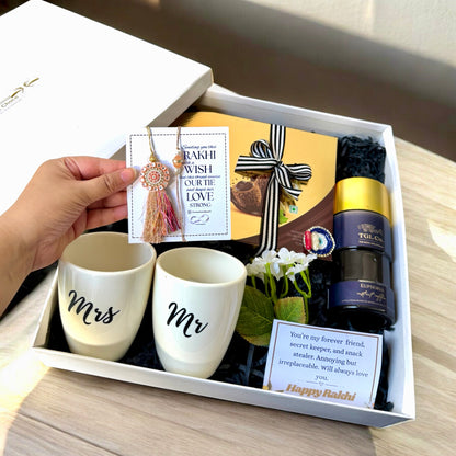 Gift set with 'Mr' and 'Mrs' mugs, a bottle, and decorative items in a box.