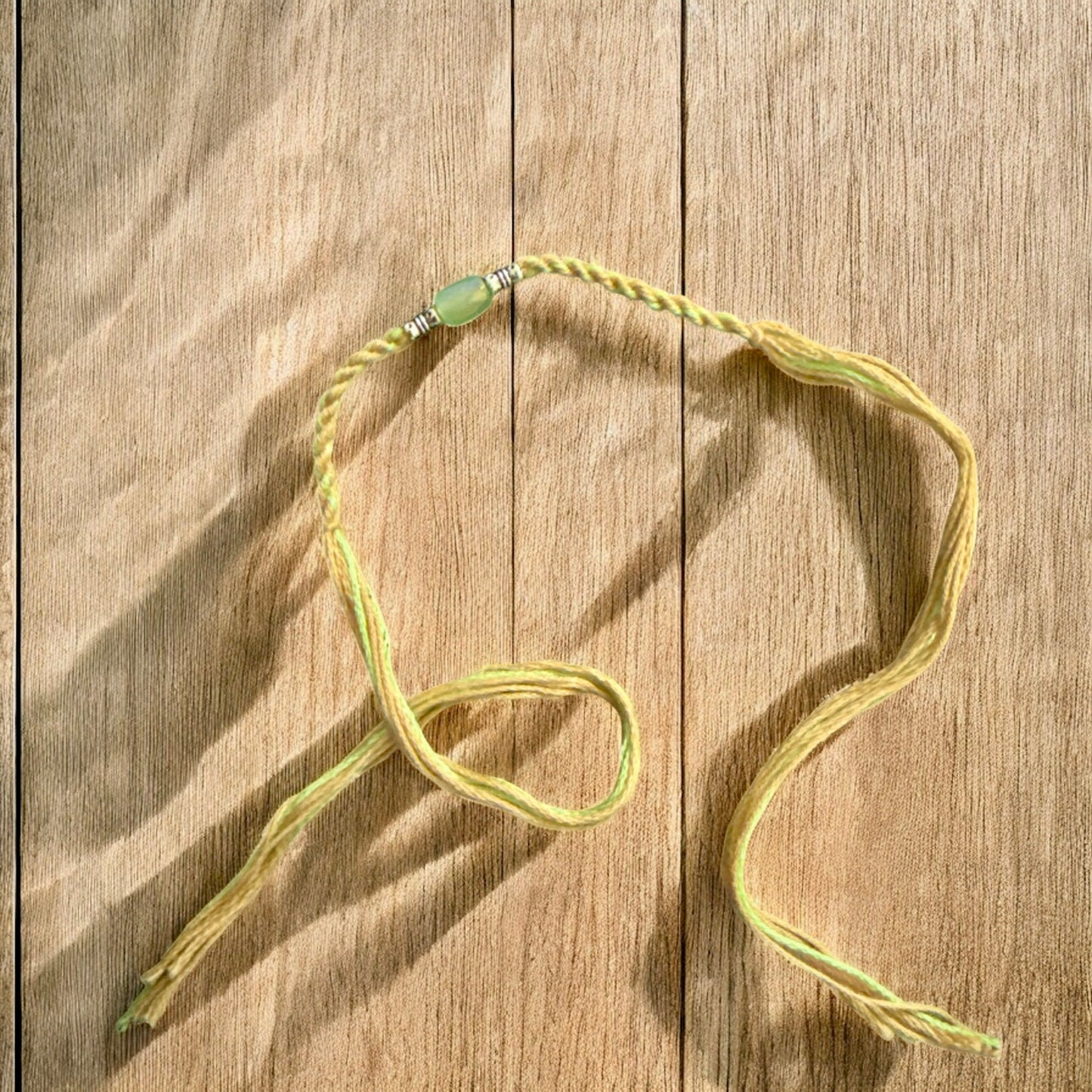 Necklace with a green pendant on a wooden surface