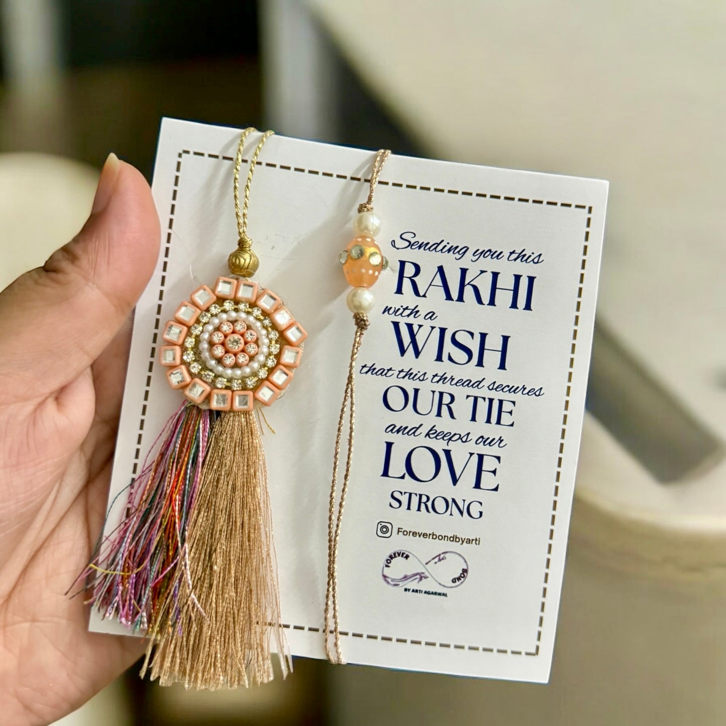 Rakhi with tassel on a card held by a hand