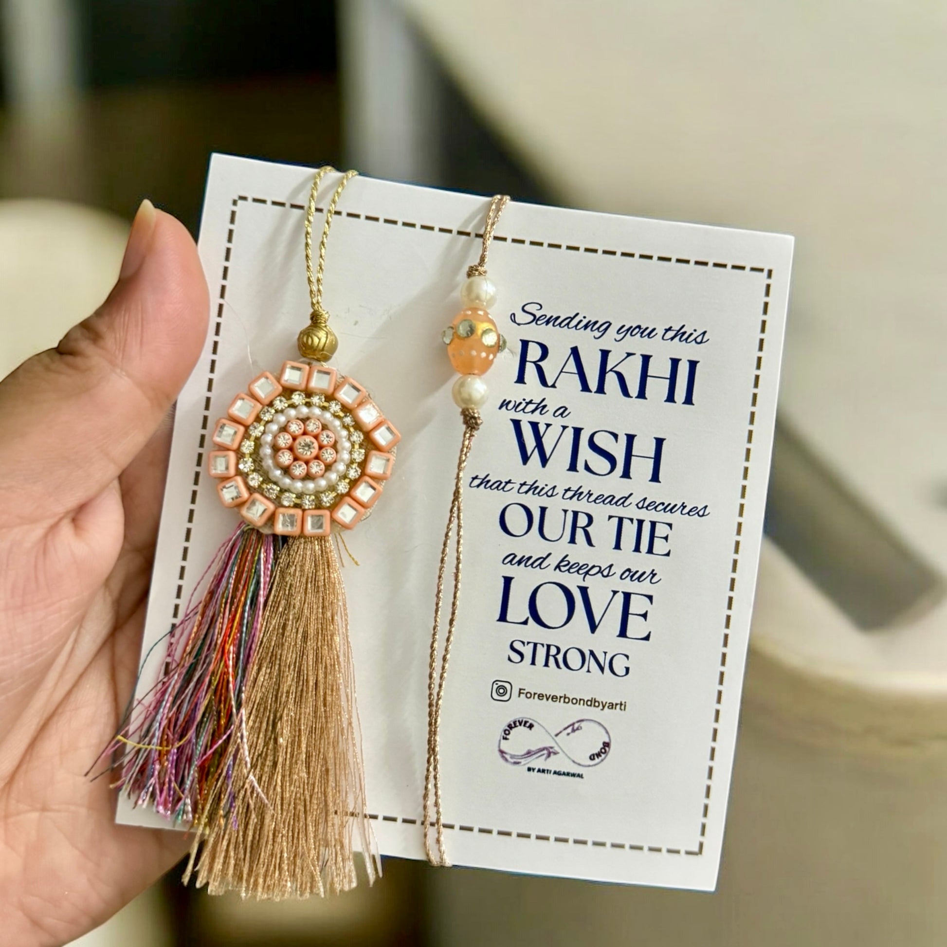 Rakhi with tassel on a card held by a hand