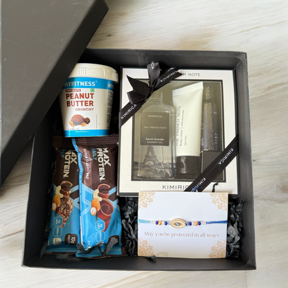 Gift box with peanut butter, protein bars, and other items on a wooden surface