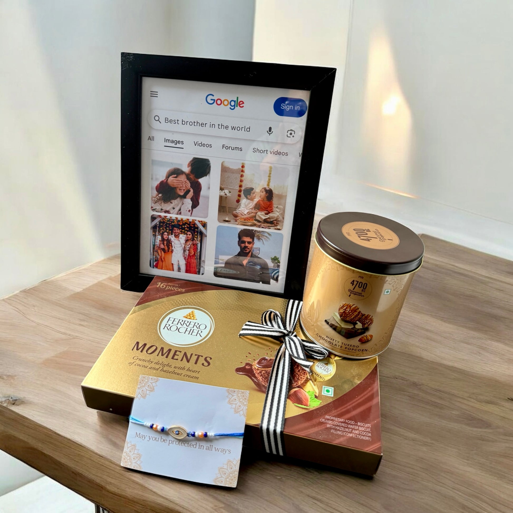 Digital photo frame, Ferrero Rocher Moments chocolate box, and a cylindrical product on a wooden surface.